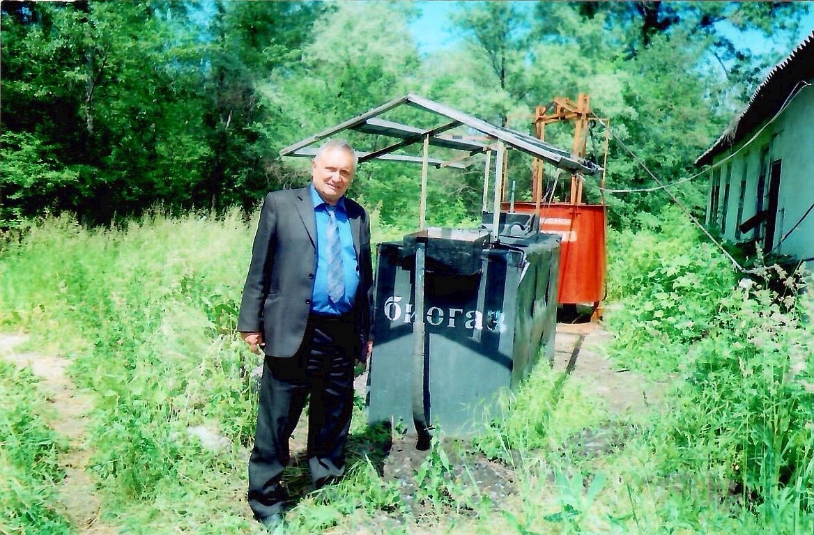 Виктор Михайлович Инюшин стоит на открытом испытательном полигоне рядом с оборудованием